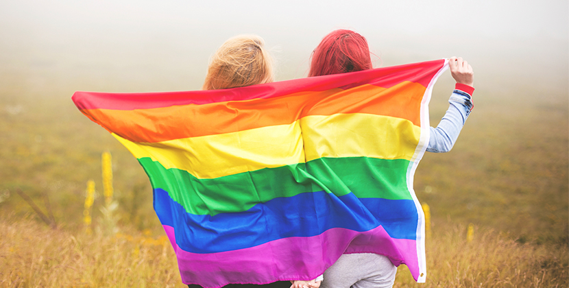 2 females holding LGBT rainbow flag